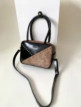 Cartera rígida negra con detalles en rojo y tachas plateadas. Tiene herrajes y cierre metálico plateado marca YKK, asa fina para llevar al hombro o en la mano y correa larga extra regulable. El interior es forrado, tiene un bolsillo con cierre enmarcado en cuero, y un segundo bolsillo plaqué.