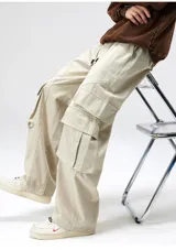 Pantalón cargo negro de corte ancho, confeccionado en gabardina de algodón. Presenta cintura elástica y regulable con cordón blanco, y múltiples bolsillos cargo laterales con costuras destacadas.