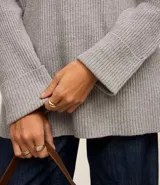 Suéter alargado de punto color rojo, con cuello alto ajustado y mangas largas ajustadas.