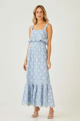 Falda larga celeste con estampado de flores blancas, cintura alta y volados en el ruedo.