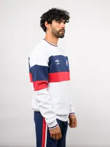 Buzo de cuello redondo confeccionado en felpa, con diseño de bloques de color en azul, rojo y blanco. Presenta el logo de Umbro y el escudo del Club Nacional de Football bordados en el frente.