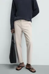 Pantalón chino de corte slim fit, confeccionado en tejido elástico. Presenta bolsillos frontales, bolsillos traseros de vivo con botón y cierre frontal con cremallera y botón.