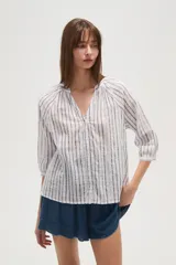 Camisa de algodón con diseño de rayas verticales y detalles bordados. Presenta cuello en V, cierre frontal con botones y mangas tres cuartos con terminación elástica.