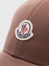 Gorra de baseball Moncler de color marrón, con visera curva, ojales bordados para ventilación y parche con el logo de la marca bordado en el frente.