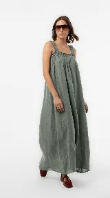 Vestido largo de lino color marrón, de silueta amplia y caída liviana, con escote cuadrado, frunces elastizados en el pecho y breteles anchos con detalles de volados.