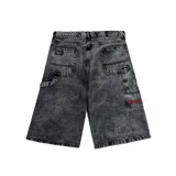 Bermuda de jean con corte baggy y lavado ácido en color negro. Presenta bolsillos laterales tipo cargo, costuras reforzadas y un bordado decorativo en color rojo en uno de los bolsillos traseros.