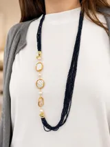 Collar largo de múltiples hilos de cristales negros, combinado con perlas barrocas y eslabones metálicos dorados.