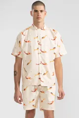 Short de algodón color crema con estampado de sirenas color naranja y amarillo, cintura elastizada con cordón ajustable, dos bolsillos laterales y un bolsillo trasero tipo parche.