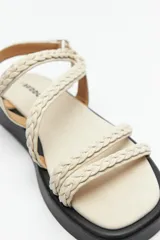 Sandalias color marrón con tiras trenzadas y ajuste de velcro en el talón. Plataforma de 3cm de alto y suela negra.
