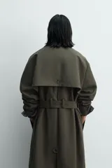 Trench de corte relajado confeccionado en tejido compacto de algodón. Presenta cuello solapa en color contraste, cierre frontal con botonadura oculta, bolsillos de vivo en la cadera y cintura ajustable con cinturón del mismo tejido. Las mangas largas cuentan con puños con trabilla y el bajo es ajustable en el centro de la espalda.