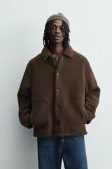 Sobrecamisa de corte relajado confeccionada en tejido con efecto borreguillo color marrón. Presenta cuello solapa, cierre frontal con botones a presión, mangas largas con puños abotonados y bolsillos frontales en la cadera.