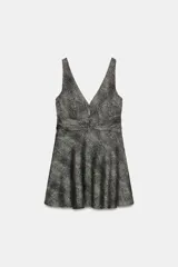 Vestido corto sin mangas con escote en pico y detalle de nudo en la cintura. Presenta un diseño acampanado con estampado de puntos pequeños en contraste.