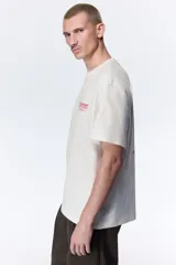 Remera de algodón blanca de corte holgado, con cuello redondo y diseño estampado en el pecho con texto en color rojo.