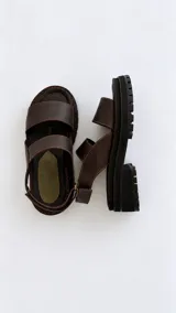 Sandalias de cuero con suela flatform track, tiras marrones y puntera con detalle de textura reptil en tono verde oliva. Cuenta con cierre de velcro en la tira trasera.