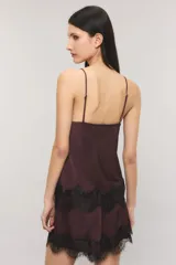 Top de satén negro de corte al bies, con tirantes regulables y escote en V profundo adornado con encaje estilo chantilly, mismo detalle que adorna el ruedo de la prenda.