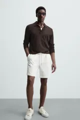 Bermuda negra de corte recto, con cintura elástica ajustable mediante cordón, pliegues frontales y bolsillos de vivo en la espalda. El bajo tiene un dobladillo vuelto.