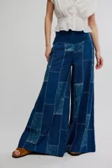 Pantalón flare de tiro alto, color azul, con diseño de patchwork y costuras visibles en contraste. Presenta perneras anchas de corte fluido.