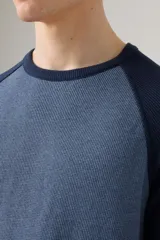 Remera de manga larga con cuello redondo, diseño raglán en dos tonos de azul y tejido térmico acanalado.