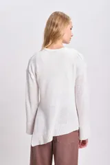 Sweater de punto color blanco, con cuello redondo y corte irregular.