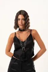 Top de satén negro con escote en V, decorado con detalles de encaje floral en el escote y en el ruedo. Presenta breteles finos ajustables y un corte asimétrico en la parte inferior.