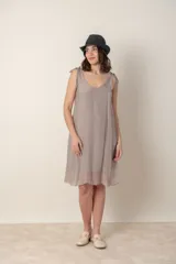Vestido corto de seda color gris oscuro, con escote redondo y tirantes anudados en los hombros. El calce es suelto y la tela es ligeramente transparente.