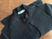 Top de bengalina color negro, con cuello mao y cierre frontal con botón de alamar. Diseño de manga larga y abertura frontal.