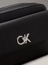 Bandolera negra de cuero sintético con correa de cadena plateada y logo CK plateado en el frente.
