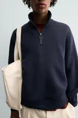 Sudadera de corte relajado confeccionada en tejido de algodón. Presenta cuello subido con cierre frontal de cremallera metálica, manga larga y acabados en rib en puños y bajo.