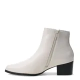 Bota tipo Chelsea de cuero color marfil, con paneles elásticos laterales, puntera redondeada y taco cuadrado bajo de color negro.