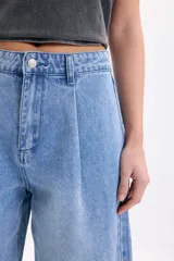 Pantalón wide leg de denim azul medio, de tiro medio con pinzas en la parte delantera y corte ancho en las piernas.