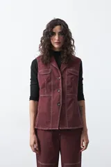 Chaleco de estilo utilitario color bordó con pespuntes blancos a contratono. Presenta solapas, cierre frontal con botones, bolsillos delanteros y un diseño estructurado.