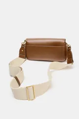 Bolso bandolera de formato alargado en color negro, con solapa frontal y cierre metálico. Incluye una correa ajustable de tejido en color crudo y herrajes dorados.