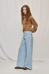 Jean wide leg blanco de tiro medio, con calce amplio y detalle de flores bordadas en los laterales.