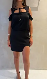 Blusa negra de corte holgado con hombros descubiertos, escote cuadrado con detalle de lazo central y mangas cortas.