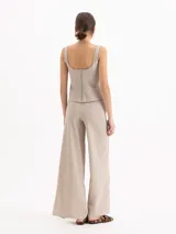 Pantalón wide leg color beige, de tiro medio-alto, con elástico en la espalda y tajos en las botamangas. Incluye cinto con hebilla del mismo tono y pinzas traseras.
