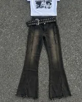Pantalon de jean color negro con efecto desgastado, corte acampanado y detalles de costuras verticales deshilachadas. Incluye un cinturón ancho con ojales metálicos.