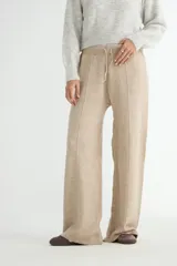 Pantalón tejido de corte recto y tiro alto, color beige, con cintura elástica ajustable mediante cordón y costura central vertical en cada pierna.