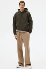 Canguro de corte holgado con capucha forrada y cordón de ajuste. Presenta hombros caídos, bolsillo frontal tipo canguro y terminaciones acanaladas en puños y ruedo. Confeccionado en mezcla de algodón con interior suave.