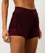 Bermuda deportiva femenina modelo runner, color bordó, con short interno incorporado. Presenta cintura elástica con cordón de ajuste y laterales con cordones ajustables. Confeccionada en tejido de tul con tecnología dry para mayor transpirabilidad.