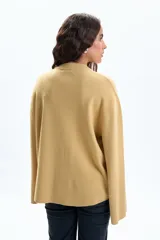 Buzo de tejido de punto color mostaza, de corte holgado, con cuello redondo acanalado y mangas anchas tipo campana.