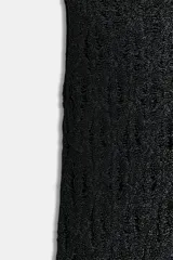 Vestido largo negro, ajustado al cuerpo, con cuello subido y manga sisa. Presenta un tejido con hilo metalizado que le da un acabado brillante.