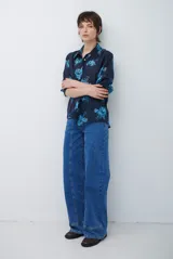 Jean de corte recto y tiro medio, color azul lavado, con costuras verticales decorativas en el frente y ruedo con dobladillo ancho.