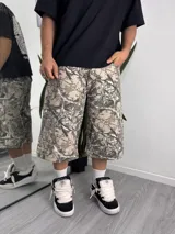 Pantalón baggy desmontable con estampado camuflado tipo Realtree de ramas y hojas en tonos beige y marrón, de corte holgado.