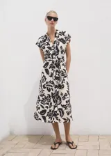 Vestido midi de viscosa con estampado floral en color crudo y negro, cuello camisero, manga corta, cierre frontal con botones y cinturón ajustable del mismo tejido.