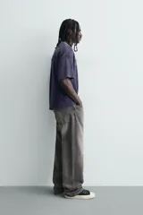 Remera de manga corta con corte relajado, confeccionada en tejido de algodón con textura tipo waffle. Presenta un efecto de lavado desgastado en color azul oscuro y estampado gráfico a contraste en el frente.