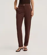 Pantalón zanahoria de poliéster y elastano color negro, de tiro alto, con cierre tradicional, bolsillos traseros y botón metálico con efecto martillado.