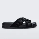 Sandalias Melissa modelo Cozy Slide M Lover II, de color negro, con suela anatómica y tiras cruzadas de tela con el nombre de la marca en relieve.
