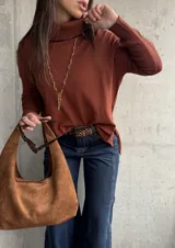 Polera de tejido de punto color chocolate, con cuello alto, mangas largas y diseño con tajos laterales en el ruedo.