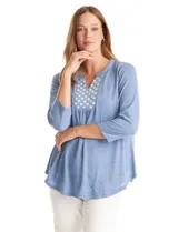 Blusa de modal texturizado en color azul, con cuello a la base y escote en V. Presenta un panel frontal decorado con apliques circulares nacarados y mangas tres cuartos.