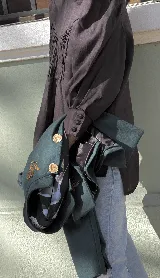 Blusa de lino color marrón oscuro con cuello alto, alforzas decorativas en el frente, mangas abullonadas y puños con botones. Presenta cierre de botones a la vista en la espalda.